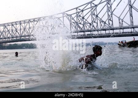 A boy jump ganga river for cool off with swimming and backside Howrah Bridge during hot weather, Kolkata Maximum Temperature In Kolkata Likely To Touch 40 Degrees on April 26,2022.The India Meteorological Department (IMD) Monday issued a heatwave warning over several districts of West Bengal from April 25 to April 28 and asked the residents of the state to avoid prolonged heat exposure. (Photo by Debajyoti Chakraborty/NurPhoto) Stock Photo