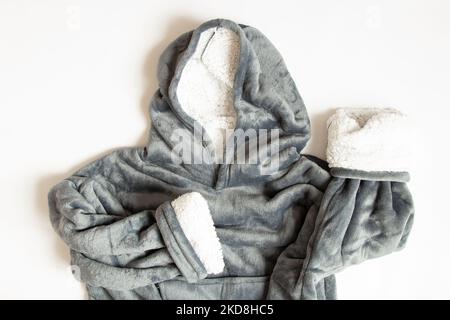 Warm gray terry home jacket with a hood lies on a white background close-up, home clothes Stock Photo