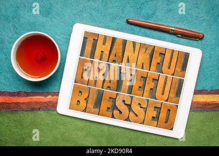 thankful, grateful and blessed inspirational words on a digital tablet with tea against abstract paper landscape, Thanksgiving theme Stock Photo