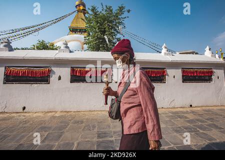 A woman doing the Kora, walking around the stupa. Boudhanath or Bouddha Stupa in Kathmandu a UNESCO World Heritage Site and a legendary place for the Newar and Tibetan Buddhist mythology with the golden part having the Eyes of Boudhanath and the praying flags. One of the most popular tourist attraction in Kathmandu, the mandala makes it one of the largest spherical stupas in Nepal and the world. The Stupa was damaged in the 2015 April earthquake. The Stupa is located on the ancient trade route from Tibet, and the Tibetan Refugees after the 1950s decided to live around Boudhanath. Nepalese peop Stock Photo
