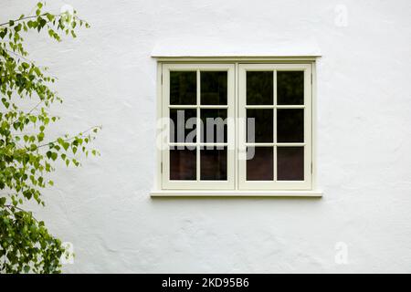 UK house exterior with wooden casement window and white wall rendering Stock Photo