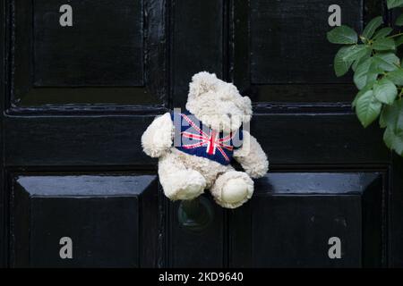 Teddy bear with union flag jumper on the exterior of a black front door to a house in England, UK Stock Photo