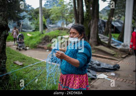 An Embera Indigenous mother helps members of Bogota's social office to dismantle a shed as Embera indigenous communities start leaving the makeshift camp mounted 8 months ago where more than 1000 indigenous people displaced by conflict lived and reached agreements with the government to be transferred to a nearby location before returning to their territories, in Bogota, Colombia May 9, 2022. (Photo by Sebastian Barros/NurPhoto) Stock Photo