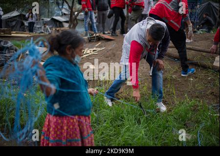 An Embera Indigenous mother helps members of Bogota's social office to dismantle a shed as Embera indigenous communities start leaving the makeshift camp mounted 8 months ago where more than 1000 indigenous people displaced by conflict lived and reached agreements with the government to be transferred to a nearby location before returning to their territories, in Bogota, Colombia May 9, 2022. (Photo by Sebastian Barros/NurPhoto) Stock Photo