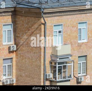 brick apartment building sunny facade with its plastic glazing of windows and balcomies, air conditioners Stock Photo