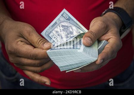 Closeup at a pack of 50 Nepalese Rupees while a man behind the counter is counting the paper currency. Money Exchange Centre office, a place for exchanging Foreign Currency to local Nepalese rupee NPR in Thamel area, in Kathmandu, the capital of Nepal on April 15, 2022. There are boards that have all the prices written according to the daily rate. Thamel has dozens of offices offering exchange services as it is a popular tourist destination. Exchange can be offered in banks, authorized forex dealers, hotels and the Tribhuvan International Airport. Most common demand to exchange is Euro, US Dol Stock Photo