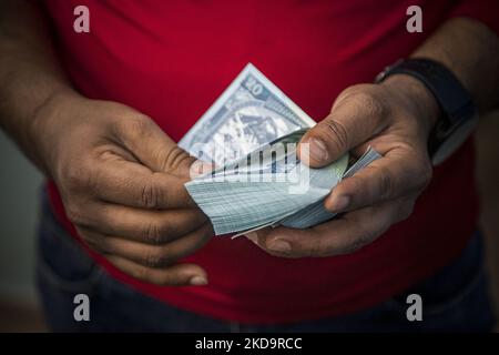 Closeup at a pack of 50 Nepalese Rupees while a man behind the counter is counting the paper currency. Money Exchange Centre office, a place for exchanging Foreign Currency to local Nepalese rupee NPR in Thamel area, in Kathmandu, the capital of Nepal on April 15, 2022. There are boards that have all the prices written according to the daily rate. Thamel has dozens of offices offering exchange services as it is a popular tourist destination. Exchange can be offered in banks, authorized forex dealers, hotels and the Tribhuvan International Airport. Most common demand to exchange is Euro, US Dol Stock Photo