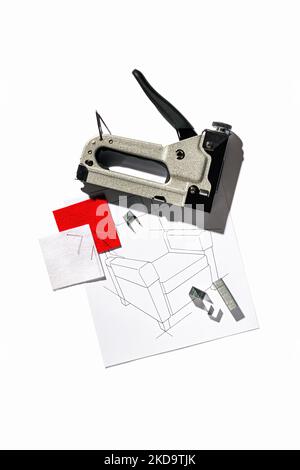 Silver furniture stapler gun with staples and the drawing of the armchair isolated on white background. Manual industrial tool Stock Photo