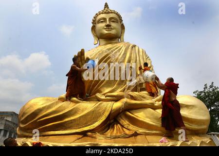 Indian Buddhist monk climbs atop a giant statue of Buddha, to wash and decorate on the eve of Buddha Purnima, a holiday traditionally celebrated for Buddha's birthday also known as Vesak celebrations, At Howrah, West Bengal, India on May 15, 2021.Buddha Purnima celebrate may 16. (Photo by Debajyoti Chakraborty/NurPhoto) Stock Photo