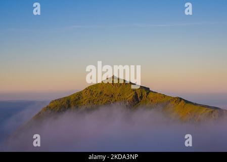 Misty sunrise view at Snowdon summit, Snowdonia National Park. Beautiful summer morning in North Wales, Snowdon summit surrounded by mist. Stock Photo