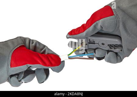 Hands in protective gloves with a stripper and an electric cable isolated on a white background. Electrician removes insulation from a three-core copp Stock Photo