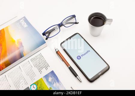 In this photo illustration a PhonePe logo seen displayed on a smartphone screen on a desk next to a cafe, a pen, glasses and a magazine in Athens, Greece on May 27, 2022. (Photo Illustration by Nikolas Kokovlis/NurPhoto) Stock Photo