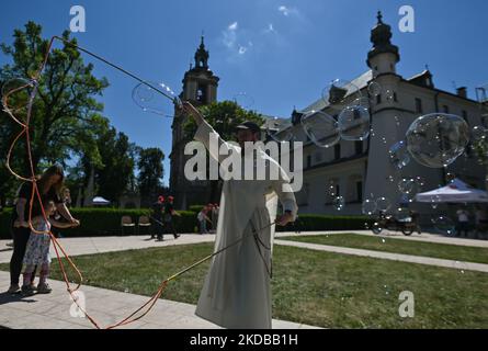 A member of the Pauline Fathers commune in Krakow blowing giant soap bubbles with loops in string held between two sticks to entertain children. The Augustinian Sisters and the Pauline Fathers organized the Polish-Ukrainian Children's Day on a half-hectare meadow behind the walls of the convent on Skalka, which was leased to the city and open to residents. On Wednesday, June 1, 2022, in Krakow, Poland. (Photo by Artur Widak/NurPhoto) Stock Photo