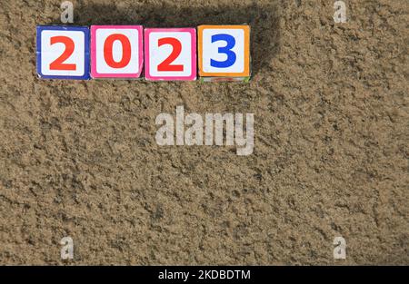 Inscription 2023. Toy square cubes and numbers on the sand on the river bank, that means coming New Year Eve. Christmas, holidays, celebration concept Stock Photo