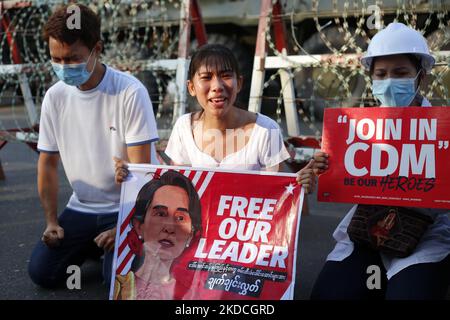 A protester cries in front of armoured vehicles as she holds a banner with a picture of Aung San Suu Kyi during a demonstration against the military coup outside the Central Bank in Yangon, Myanmar on February 15, 2021 (reissued June 23, 2022). The junta confirmed today that ousted civilian leader Aung San Suu Kyi had been moved to a prison in Naypyitaw. (Photo by STR/NurPhoto) Stock Photo