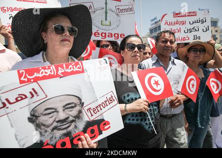 Supporters of the Free Destourian Party (Arabic: Al-Dustur al-Hurr) hold placards, flags of Tunisia and a poster of the founding chairman of the International Union of Muslim Scholars, Yusuf al-Qaradawi that reads Dégage(get out), terrorist, during a demonstration held outside the building of the embassy of the Emirate of Qatar in Tunis, Tunisia, on June 24, 2022 to protest against the Tunisian branch of the International Union of Muslim Scholars. Demonstrators also protested against the Qatari charities in Tunisia as well as against the Qatar Fund For Development (QFFD). The president of the  Stock Photo