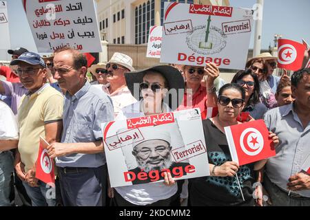 Supporters of the Free Destourian Party (Arabic: Al-Dustur al-Hurr) hold placards, flags of Tunisia and a poster of the founding chairman of the International Union of Muslim Scholars, Yusuf al-Qaradawi that reads Dégage(get out), terrorist, during a demonstration held outside the building of the embassy of the Emirate of Qatar in Tunis, Tunisia, on June 24, 2022 to protest against the Tunisian branch of the International Union of Muslim Scholars. Demonstrators also protested against the Qatari charities in Tunisia as well as against the Qatar Fund For Development (QFFD). The president of the  Stock Photo