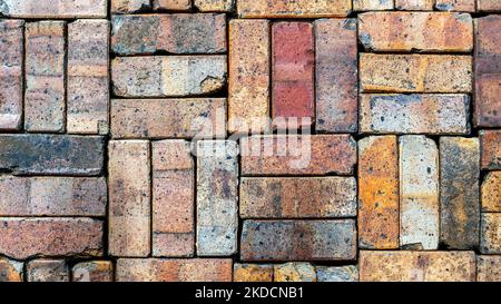 Stacked wall of colorful old reclaimed bricks background Stock Photo