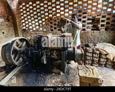 Man places raw clay into a large machine to prepare it before it is sculpted onto pots and vases at a pottery workshop in Neyyattinkara, Thiruvananthapuram (Trivandrum), Kerala, India, on May 28, 2022. (Photo by Creative Touch Imaging Ltd./NurPhoto) Stock Photo