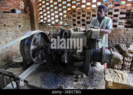 Man places raw clay into a large machine to prepare it before it is sculpted onto pots and vases at a pottery workshop in Neyyattinkara, Thiruvananthapuram (Trivandrum), Kerala, India, on May 28, 2022. (Photo by Creative Touch Imaging Ltd./NurPhoto) Stock Photo