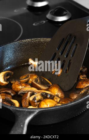 https://l450v.alamy.com/450v/2kdcxt2/frying-chestnut-mushrooms-in-a-cast-iron-frying-pan-on-an-electric-hob-stove-2kdcxt2.jpg