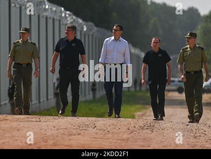 (L-R) Brigadier General Grzegorz Niemiec, Deputy Chief Commandant of the Border Guard, Maciej Wasik, secretary of state in the Ministry of Internal Affairs and Administration, Mateusz Morawiecki, Prime Minister of Poland, Mariusz Kami?ski, Minister of Interior and Administration and Major General Tomasz Praga, Chief Commandant of the Border Guard, walking near the new fence on the Polish-Belarusian border near the village of Nowdziel. Prime Minister Mateusz Morawiecki (Center) appeared on the Polish-Belarusian border at the border wall, which the Polish government called a 'physical barrier'.  Stock Photo