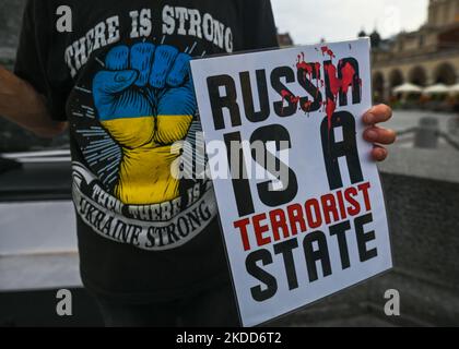 A protester holds a placard with words 'Russia Is A Terrorist State'. Ukrainians living in Krakow seen during their 131st day the 'NATO CLose The Sky' protest at Adam Mickiewicz statue in Krakow's Main Market Square. On Monday, July 04, 2022, in Main Market Square, Krakow, Poland. (Photo by Artur Widak/NurPhoto) Stock Photo