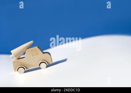 Wooden toy, silhouette of Christmas tree on toy car on colored layered paper background. Xmas holiday blue celebration background. Copy-space, place Stock Photo