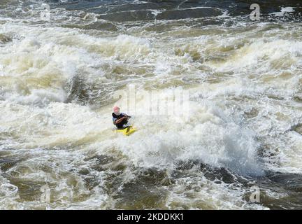 Kayaking in very rough rapids. The river is violent with a lot of turbulent waves and spray. The face of the person in the kayak is not identifiable. Stock Photo