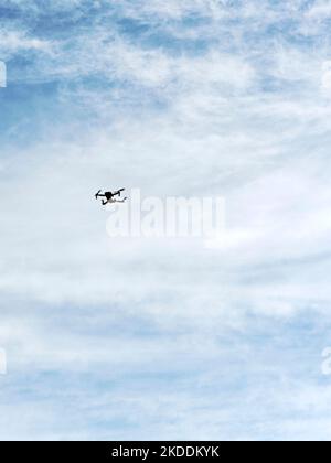Small four blade flying drone being flown in an empty sky. Stock Photo
