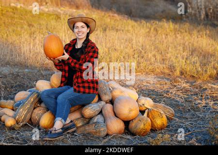 woman farmer with heap of ripe pumpkins on plantation Stock Photo