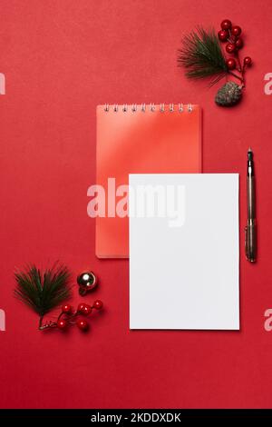 an empty notepad, pen and christmas decorations on a red background with space for your own text or image Stock Photo