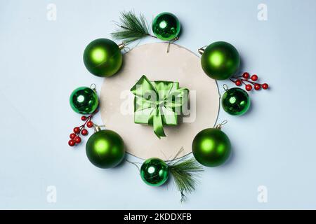 some green christmas ornaments on a white surface with red berries and pine cones around the frame, as well for decoration Stock Photo