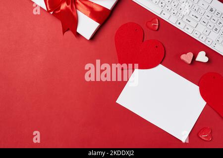 two hearts on top of a computer keyboard with a red ribbon around it and white envelopes in the background Stock Photo