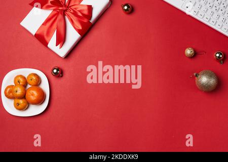 an office desk with a computer, keyboard and christmas ornaments on the table top view from above is a bowl of oranges Stock Photo