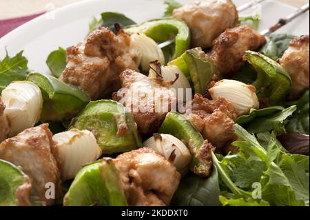 Grilled chicken skewers with green pepper and onions served with a fresh leafy green salad , close up view on three kebabs Stock Photo