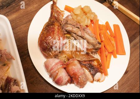 Tasty roast turkey dinner with pigs in blankets, or bacon wrapped pork sausages, served with carrots on a white plate Stock Photo