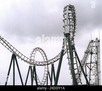 Amusement park roller coaster ride against cloudy sky showing the track doing loop the loops with sharp descents Stock Photo