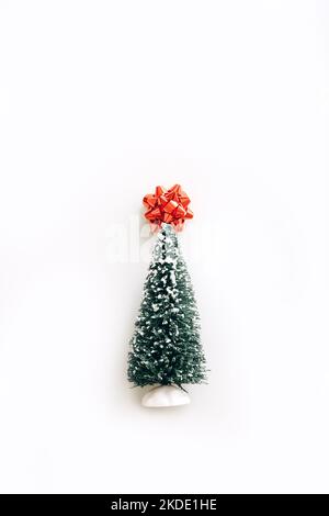 Lovely artificial mini Christmas tree with red bow on top over white background. Little Christmas tree Stock Photo
