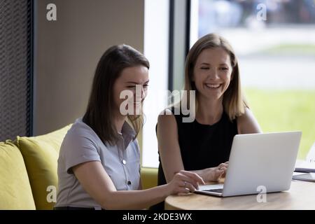 Attractive women sit at table staring at laptop at workplace Stock Photo