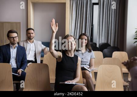 Woman employee, training participant having question raise arm during workshop Stock Photo