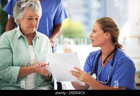 Talking through possible treatments. a doctor discussing treatments with a senior woman sitting in wheelchair in a hospital. Stock Photo