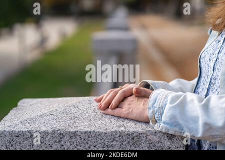 Women's hands leaning on a stone column in a public park in a relaxed attitude, photo copyspace. Stock Photo