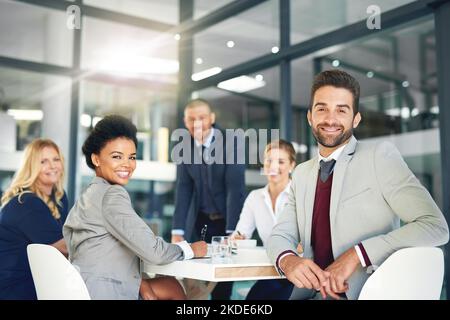 Were here to make it big in the corporate world. Portrait of a group of businesspeople working in an office. Stock Photo