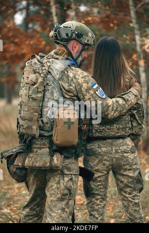 Ukrainian soldiers man and woman dressed military uniform at front line. Couple in love at war during russian military invasion of Ukraine. Stock Photo