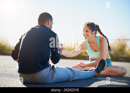 Helping each other gain a healthier lifestyle. a sporty young couple stretching before a run outside. Stock Photo