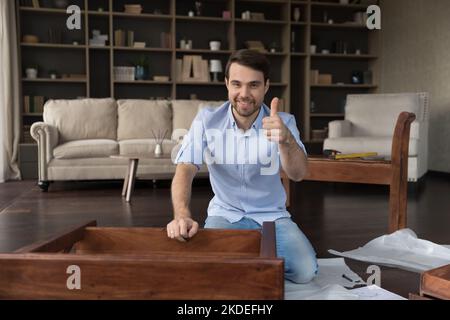 Man showing thumb up after assembling wooden table Stock Photo