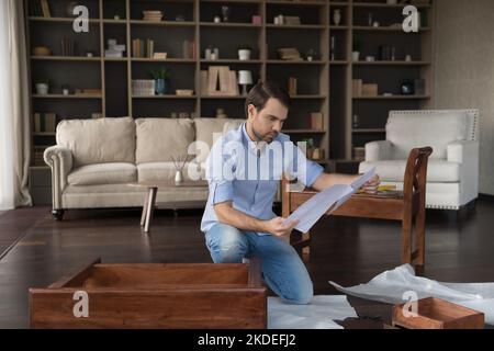 Man learning instruction before assembling new wooden table Stock Photo