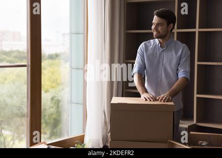 Man poses indoors with heap of packed belongings in boxes Stock Photo