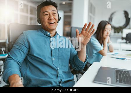 Smiling asian businessman talking phone with client while sitting in office on colleague background Stock Photo